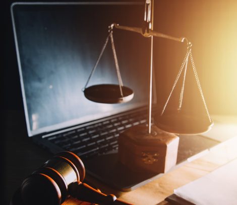 law legal technology concept. judge gavel on computer with scales of justice on desk of lawyer.
